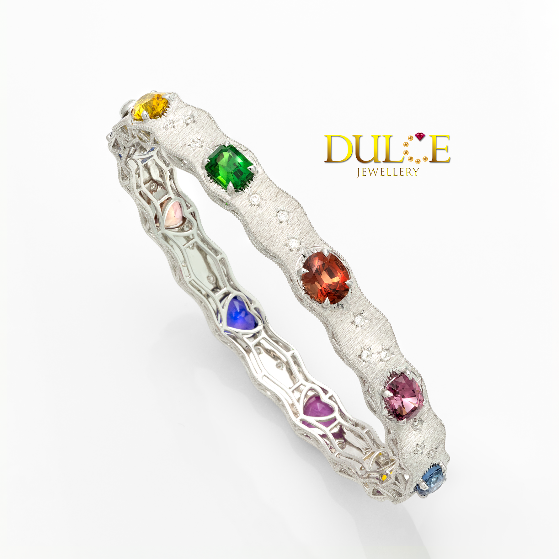 18K Bangle with colorful gemstones like sapphire, spinel and tsavorite on a white background, featuring the Dulce Jewellery logo.