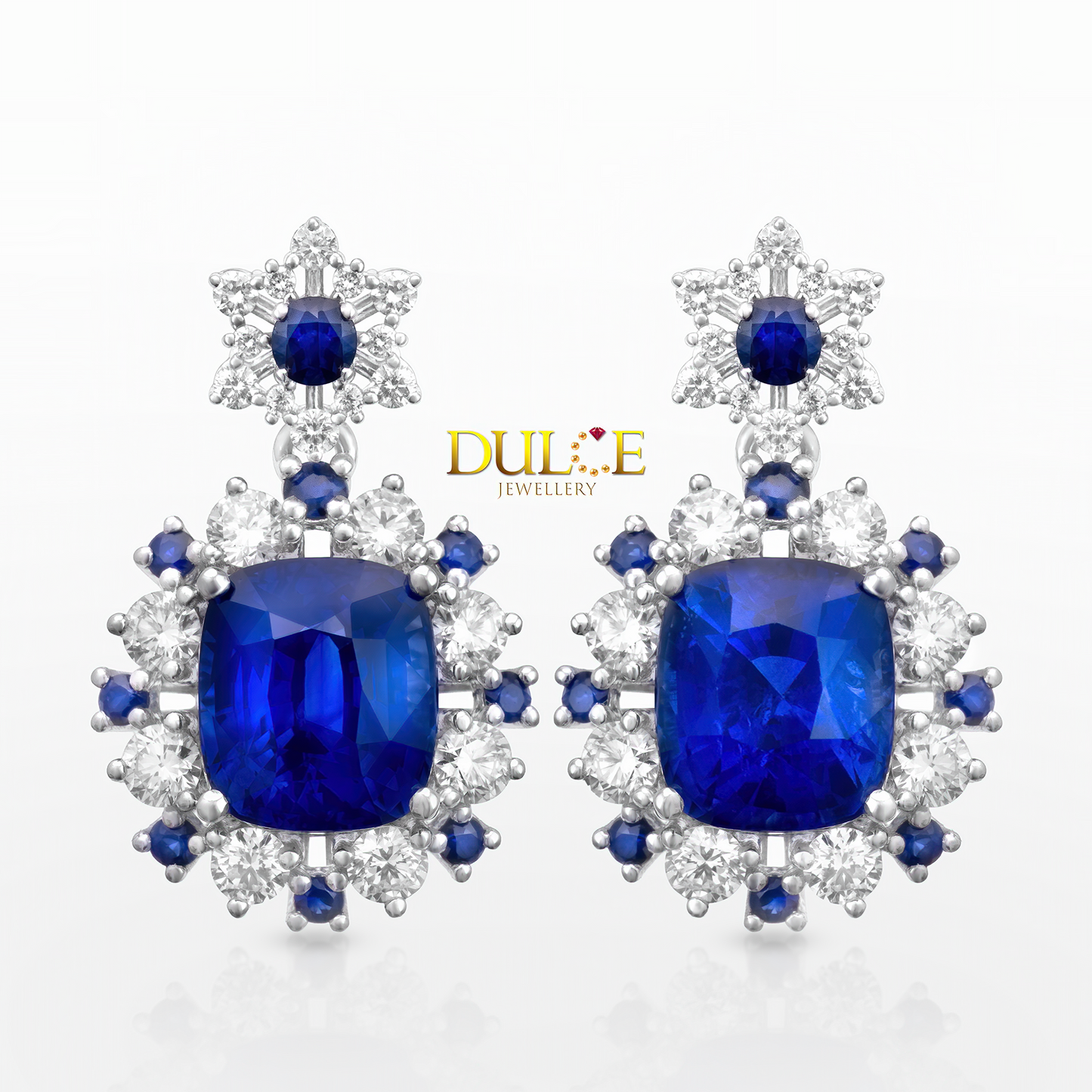 Pair of blue sapphire gemstone earrings with diamond accents on a white background, featuring the Dulce Jewellery logo.