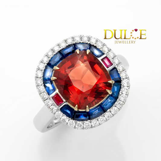 Ring with red gemstone and blue and red accents on a white background, featuring the Dulie Jewellery logo.