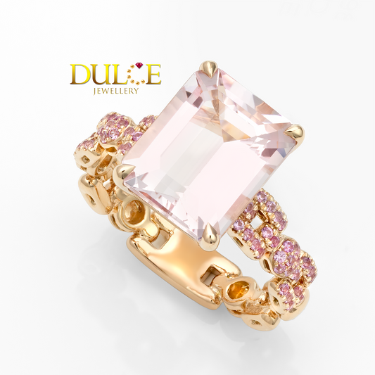 Gold ring with a large pink gemstone and smaller pink stones on a white background, featuring the Dulce Jewellery logo.