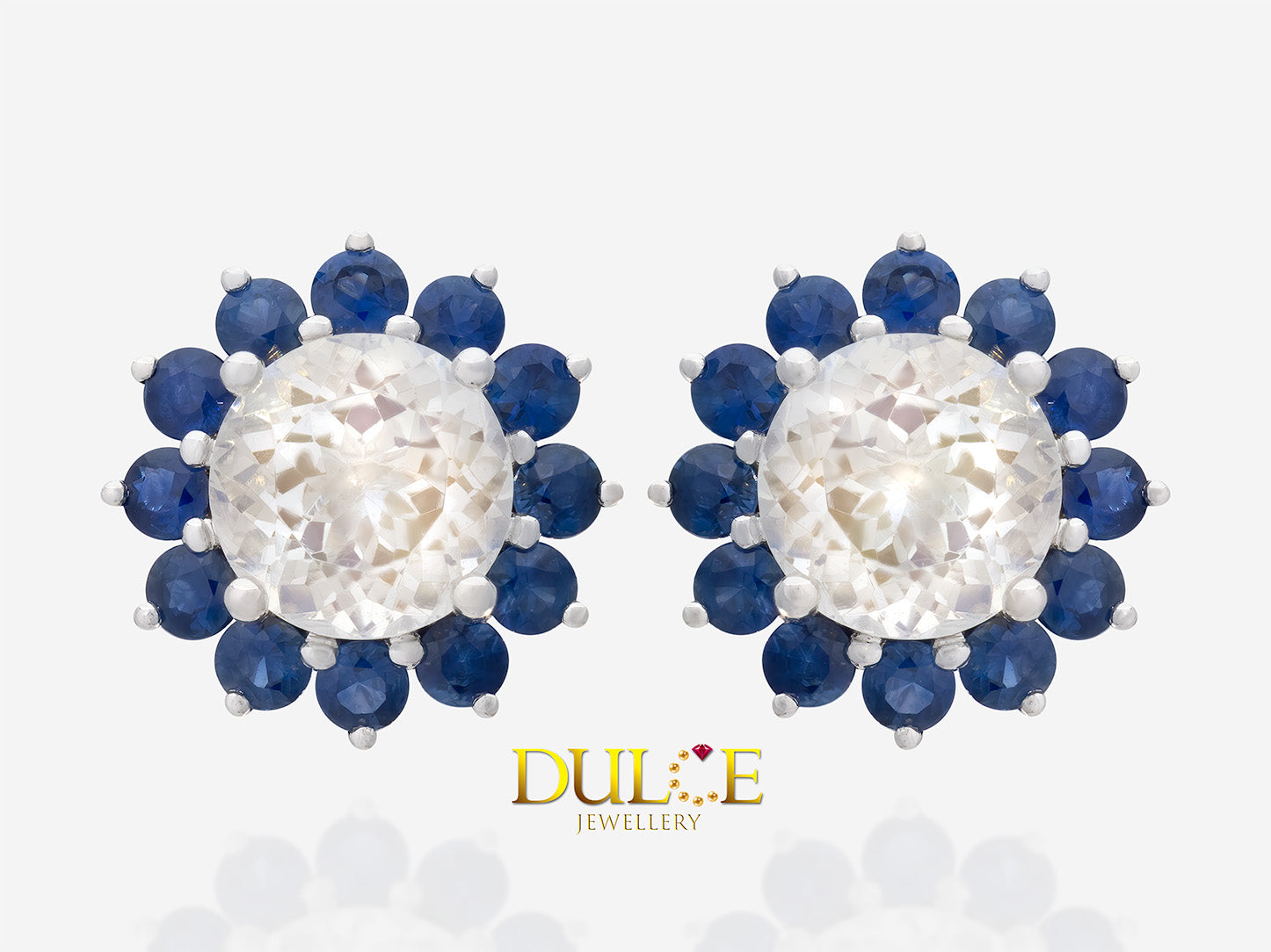 Round-shaped moonstone surrounded by a sparkling halo of blue sapphires, set in an elegant metal design.